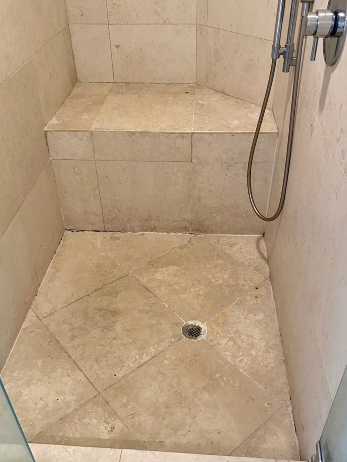 Stone shower with stained grout and mould before cleaning